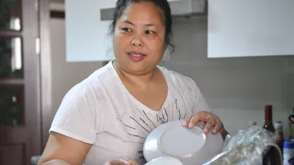 A woman domestic worker holding a dish.